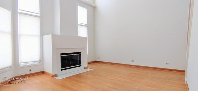unfurnished living room featuring baseboards, a tiled fireplace, and wood finished floors