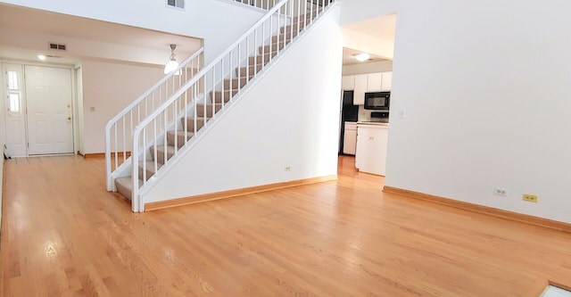 staircase with baseboards, wood finished floors, and visible vents