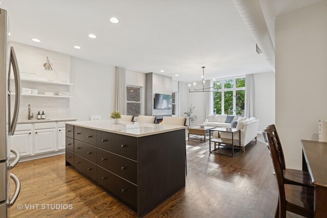 kitchen with wood finished floors, dark brown cabinetry, light countertops, white cabinetry, and a chandelier