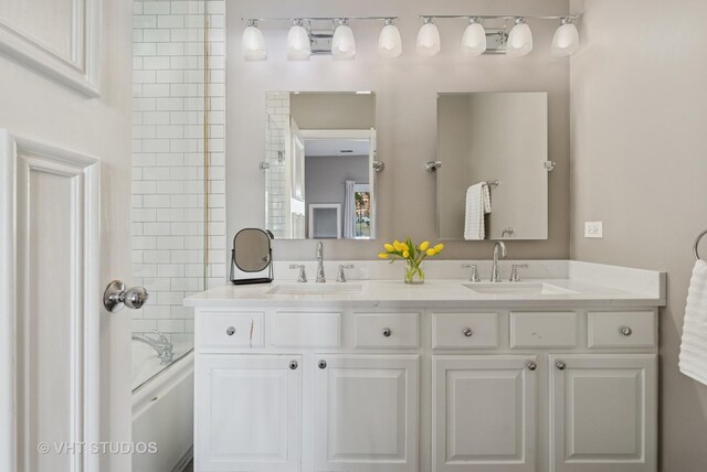 bathroom featuring a sink, bathing tub / shower combination, and double vanity