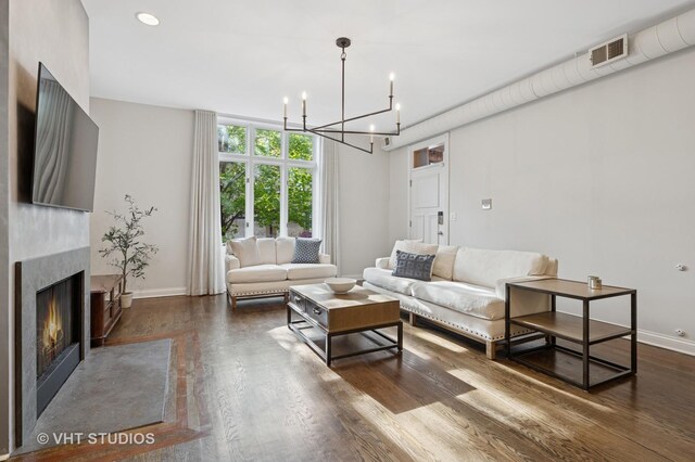 living area featuring a chandelier, baseboards, visible vents, and wood finished floors