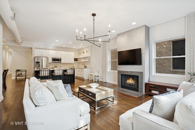 living room with an inviting chandelier, recessed lighting, a fireplace, and dark wood-style flooring