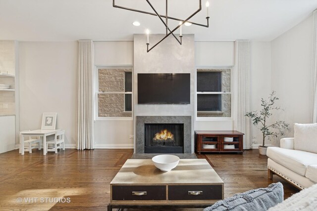 living room featuring a fireplace with flush hearth, wood finished floors, baseboards, a chandelier, and recessed lighting