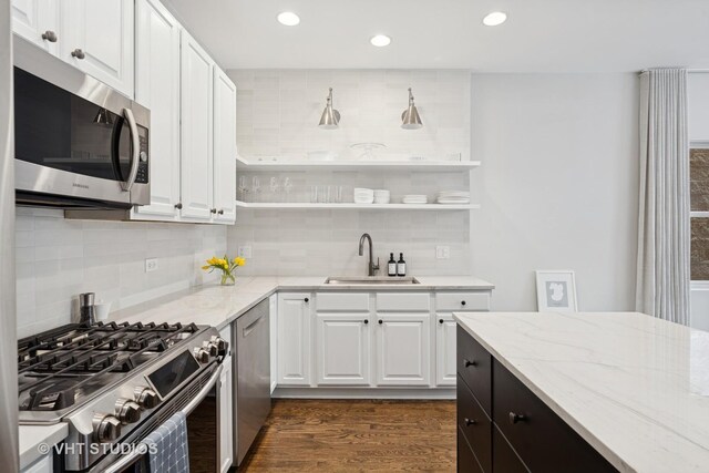 kitchen featuring white cabinets, open shelves, a sink, stainless steel appliances, and decorative backsplash