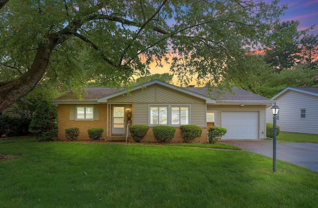 ranch-style home with driveway, a garage, a front yard, and brick siding