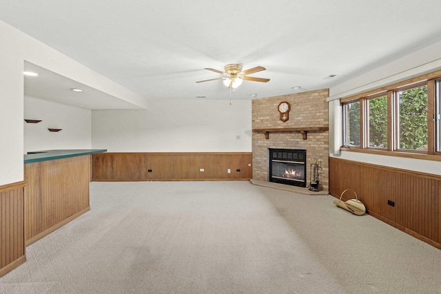 unfurnished living room with a wainscoted wall, a ceiling fan, and wood walls