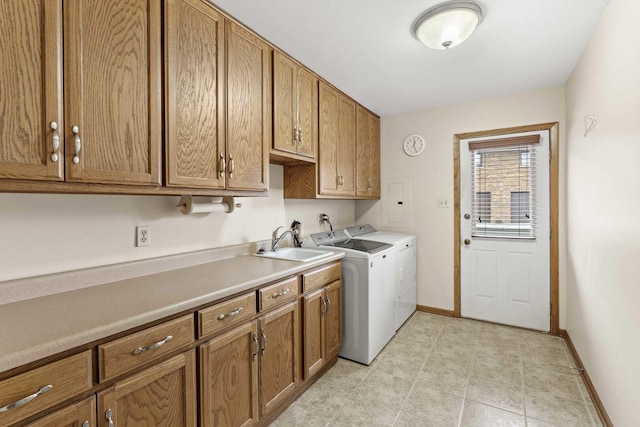 laundry area with baseboards, a sink, cabinet space, and washing machine and clothes dryer