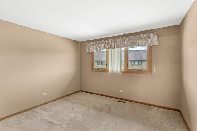 spare room featuring visible vents, baseboards, and light carpet
