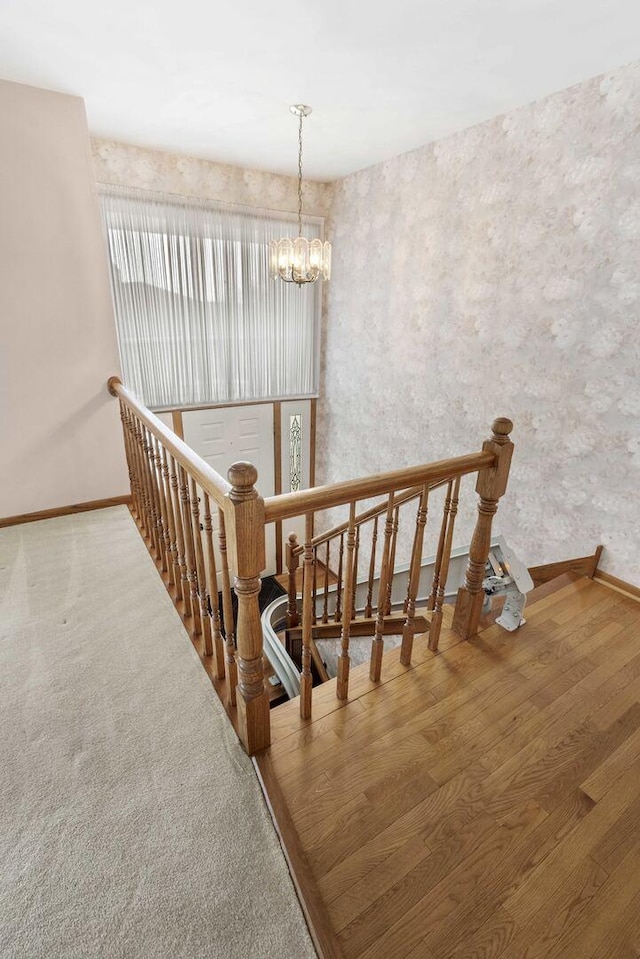 staircase with an inviting chandelier and baseboards