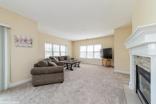 carpeted living area featuring baseboards and a stone fireplace