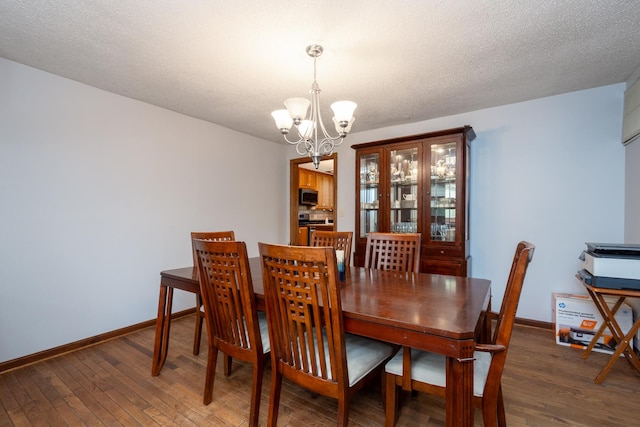 dining room with a chandelier, wood finished floors, and baseboards