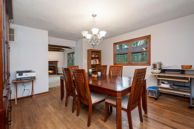 dining room featuring a chandelier, wood-type flooring, and a warm lit fireplace