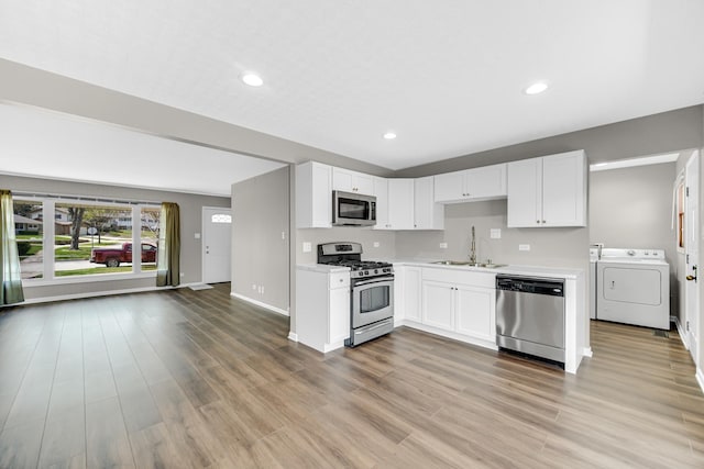 1595 Highland Blvd, Hoffman Estates, IL 60169 - kitchen with independent washer and dryer, light countertops, white cabinets, a sink, and appliances with stainless steel finishes