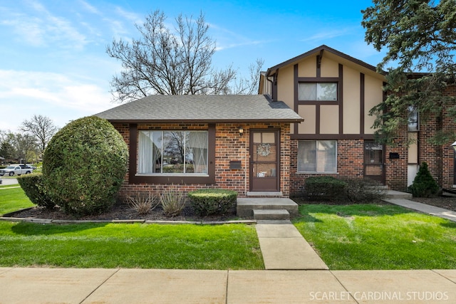 view of front of home featuring a shingled roof, stucco siding, a front lawn, and brick siding