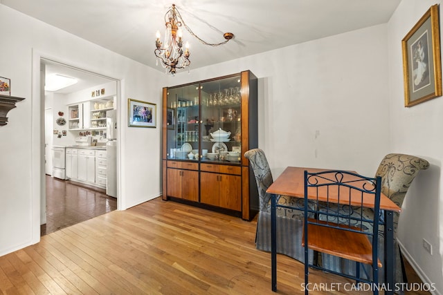 dining space featuring wood-type flooring, baseboards, and a chandelier
