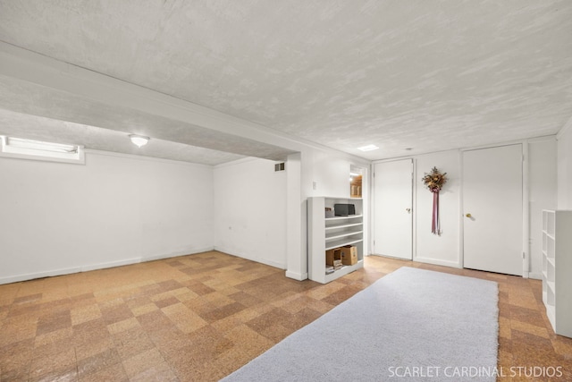 finished below grade area featuring baseboards, a textured ceiling, and visible vents