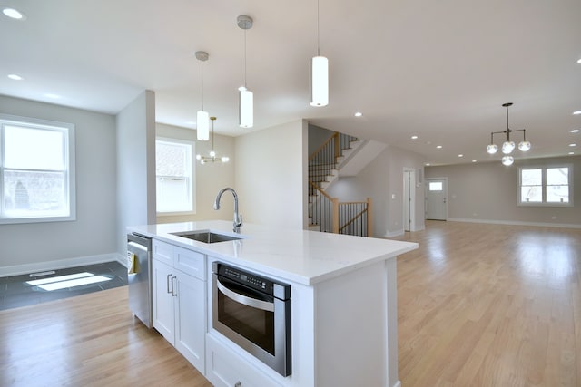 2123 N Austin Ave, Chicago, IL 60639 - kitchen featuring a kitchen island with sink, a chandelier, light stone counters, a sink, and stainless steel appliances