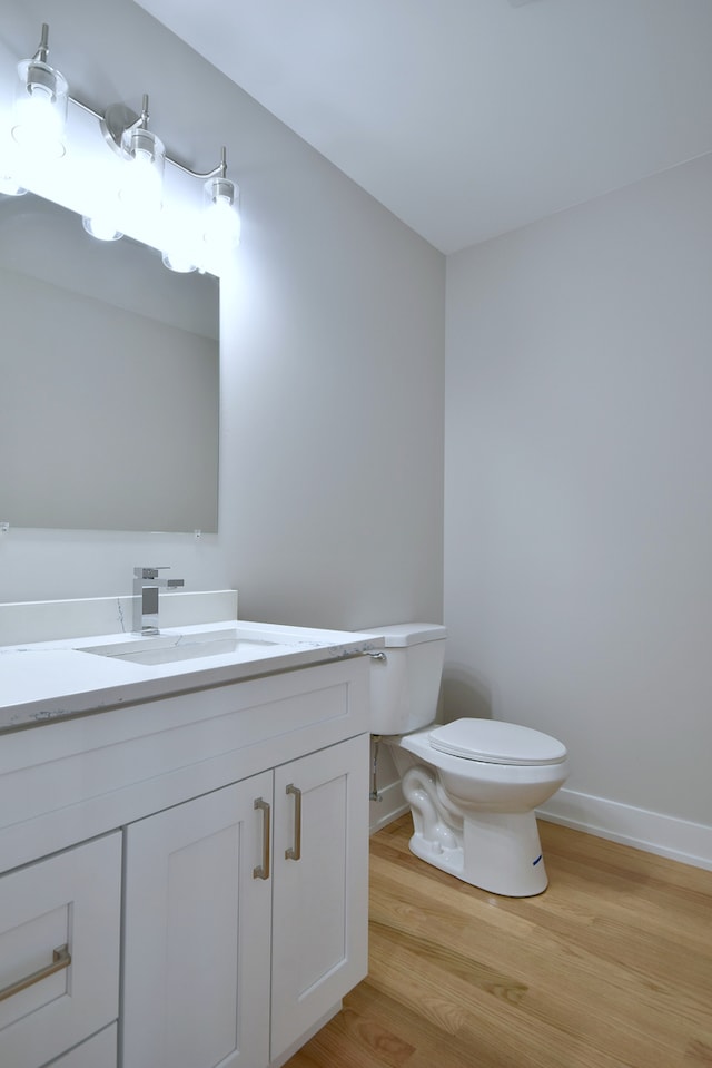 2123 N Austin Ave, Chicago, IL 60639 - bathroom with toilet, baseboards, wood finished floors, and vanity