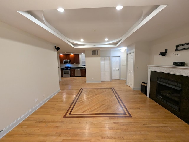 6912 N Lakewood Ave Unit 1W, Chicago, IL 60626 - unfurnished living room with light wood finished floors, a raised ceiling, a fireplace, recessed lighting, and baseboards