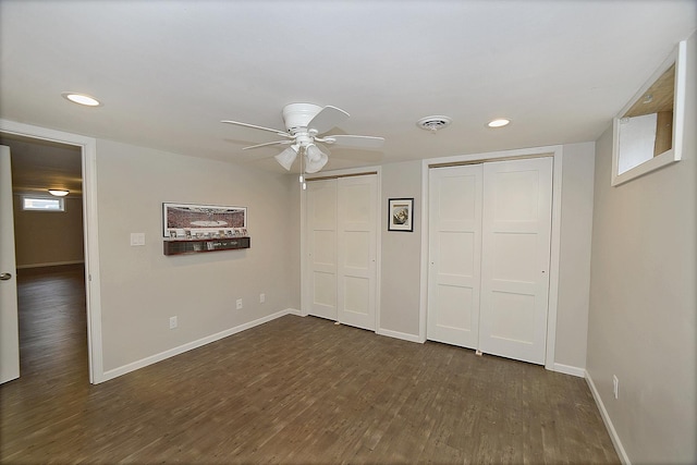 unfurnished bedroom with baseboards, recessed lighting, multiple closets, and dark wood-style flooring