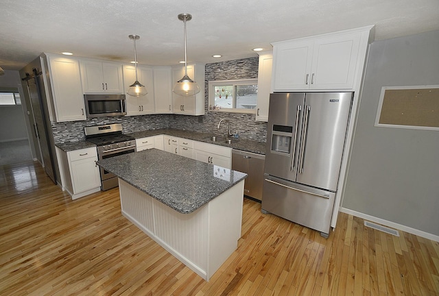 kitchen featuring light wood-style floors, a sink, tasteful backsplash, and stainless steel appliances