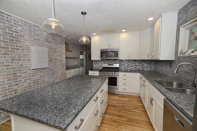 kitchen with white cabinets, stainless steel appliances, a sink, and light wood-style floors