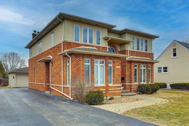 view of front of house with brick siding, a detached garage, stucco siding, an outbuilding, and a chimney