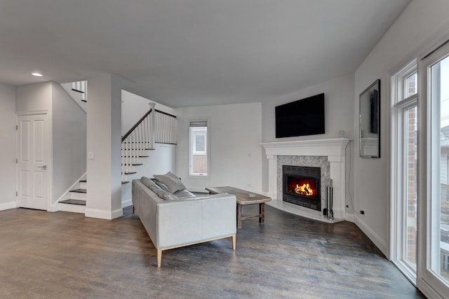 living area featuring dark wood-style flooring, a fireplace, a wealth of natural light, and stairway