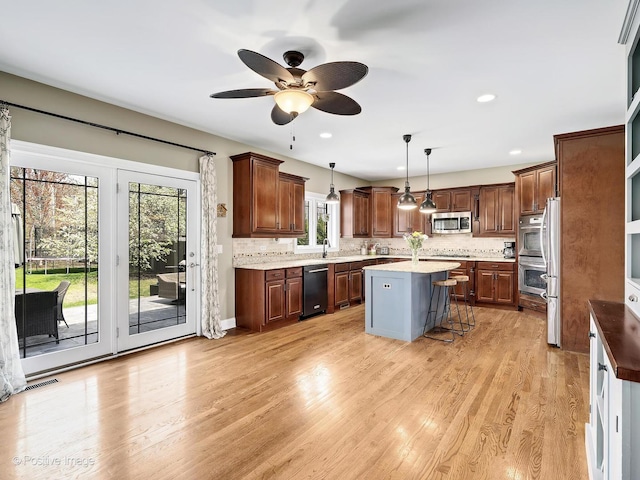kitchen featuring ceiling fan, a center island, a sink, light wood finished floors, and black appliances