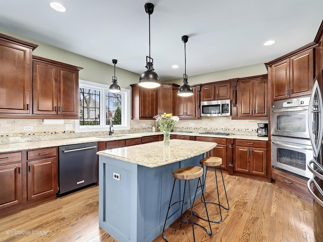 kitchen with decorative backsplash, a center island, a sink, stainless steel appliances, and light wood-style flooring