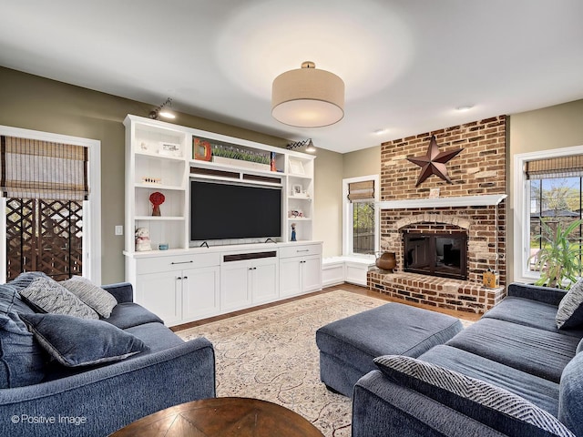 living room featuring light wood-style flooring and a brick fireplace