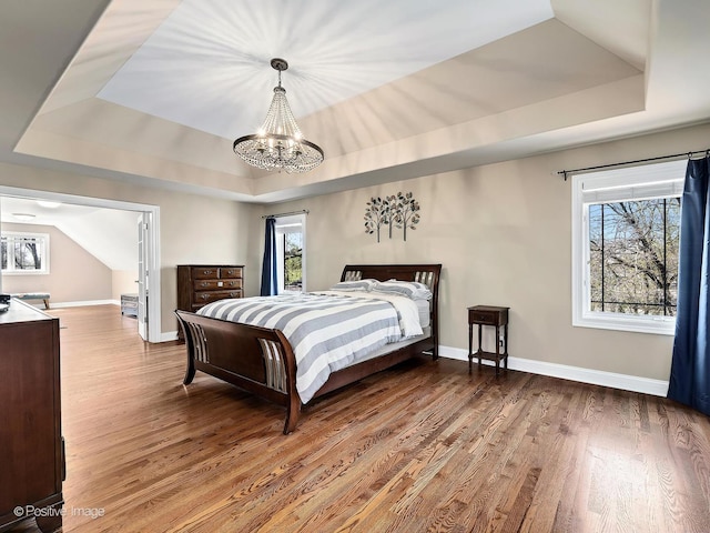 bedroom with a raised ceiling, a chandelier, and multiple windows