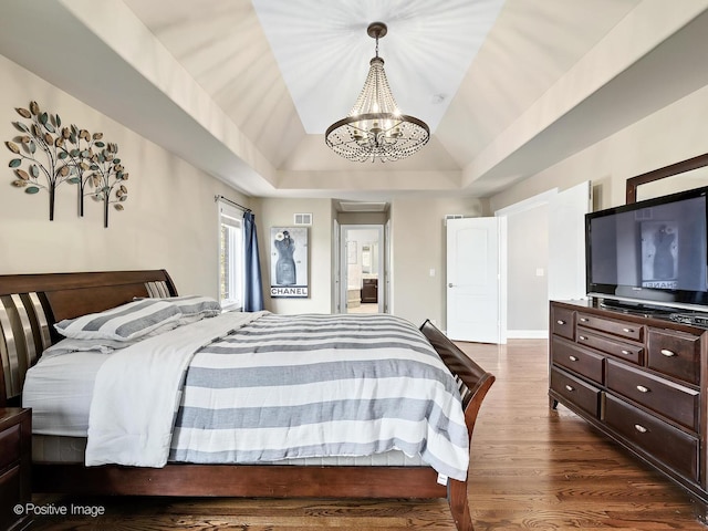 bedroom with visible vents, dark wood-style floors, a raised ceiling, a chandelier, and vaulted ceiling