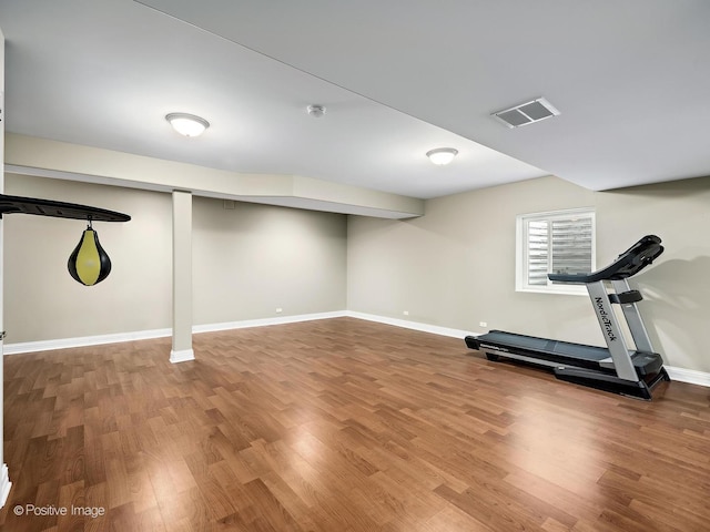 exercise room featuring baseboards, visible vents, and wood finished floors