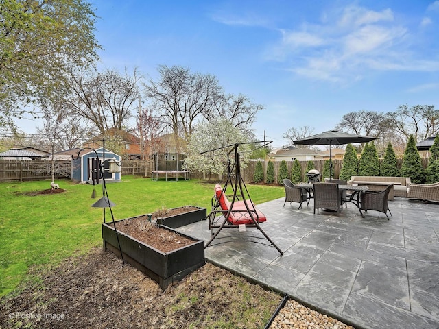 view of patio featuring a fenced backyard, a storage shed, a trampoline, an outbuilding, and outdoor dining space