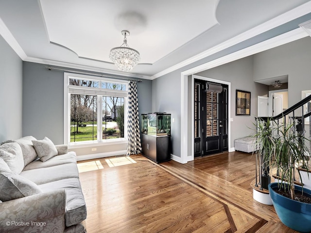 living room with baseboards, ornamental molding, wood finished floors, and a chandelier