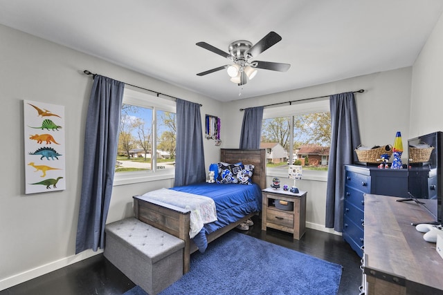 bedroom featuring baseboards, ceiling fan, multiple windows, and wood finished floors