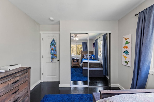 bedroom with baseboards, a closet, and dark wood finished floors