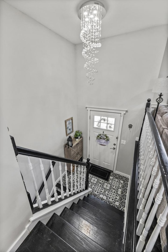 entryway with baseboards, a notable chandelier, and stairway