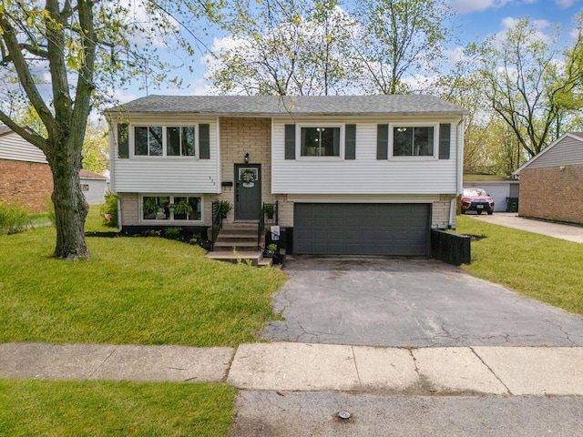 bi-level home featuring an attached garage, a front yard, and aphalt driveway