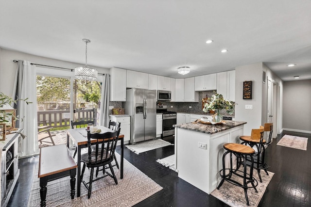 kitchen featuring recessed lighting, white cabinets, a breakfast bar, and stainless steel appliances
