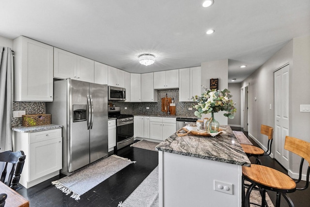 kitchen featuring a center island, backsplash, stainless steel appliances, and white cabinetry
