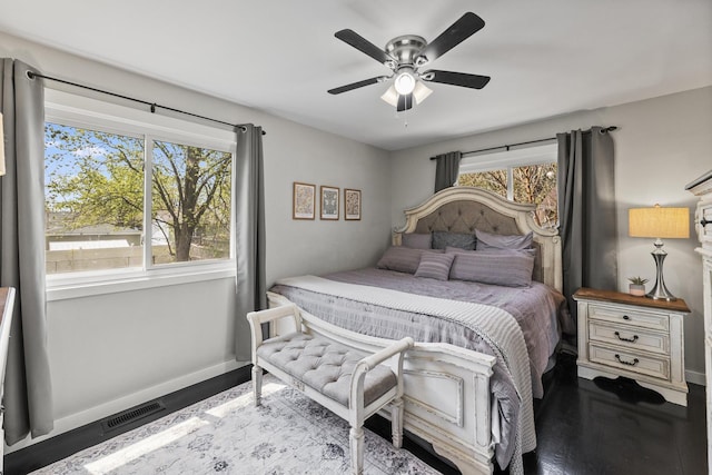 bedroom featuring baseboards, ceiling fan, wood finished floors, and visible vents