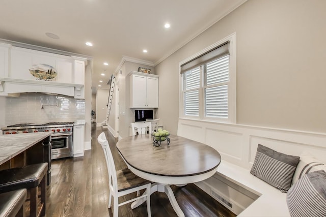 dining room with crown molding, dark wood finished floors, recessed lighting, and a wainscoted wall