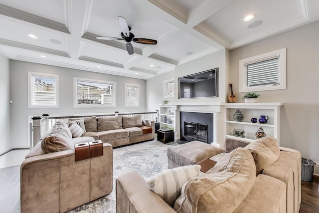 living room featuring a ceiling fan, beamed ceiling, coffered ceiling, a glass covered fireplace, and wood finished floors