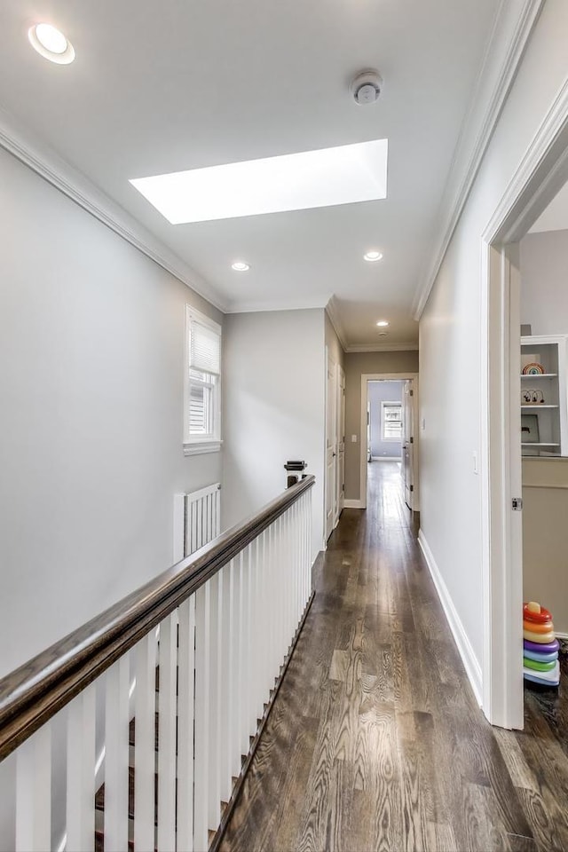 corridor with a skylight, crown molding, dark wood-type flooring, recessed lighting, and baseboards
