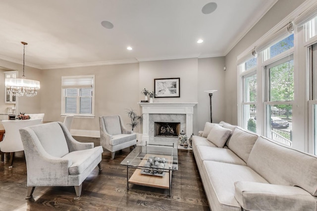 living room featuring crown molding, wood finished floors, a premium fireplace, baseboards, and a chandelier