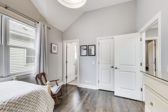 bedroom featuring lofted ceiling, dark wood finished floors, multiple windows, a closet, and baseboards