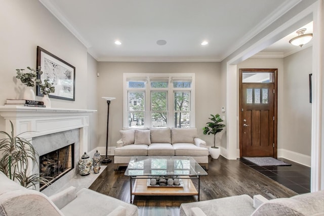 living room featuring baseboards, a premium fireplace, crown molding, recessed lighting, and wood finished floors