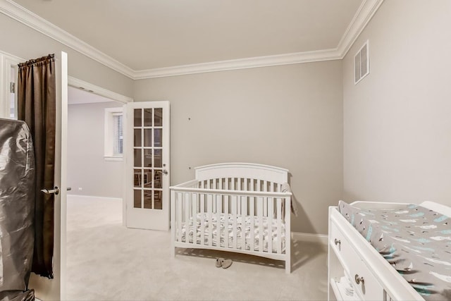 bedroom featuring ornamental molding, light carpet, baseboards, and a crib